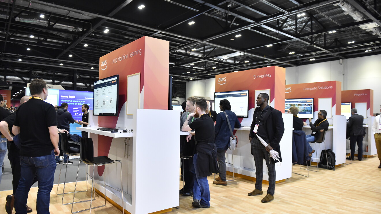 Group of people standing by screens at AWS conference 