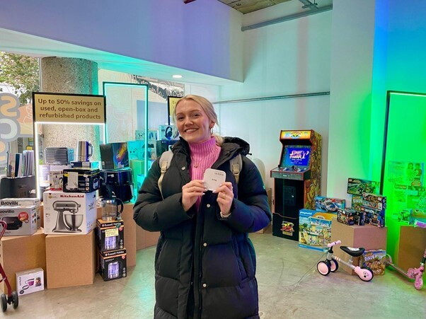 A young woman holding an airtag at the Amazon Second Chance Store 