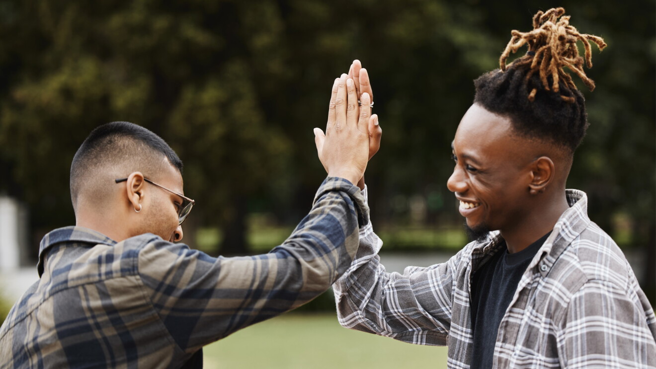 An image of two men high-fiving. They are both wearing flannel shirts.