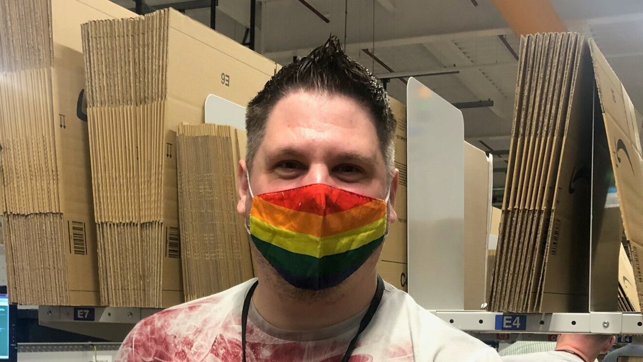 Dean Barnes, an associate at Amazon's fulfilment centre in Durham, pictured at his packing station wearing a rainbow coloured face mask.