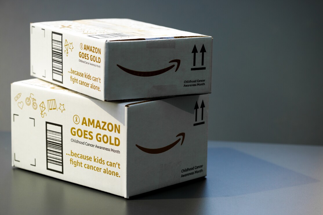 Two Amazon boxes bearing the words "Amazon Goes Gold" and "because kids can't fight cancer alone."