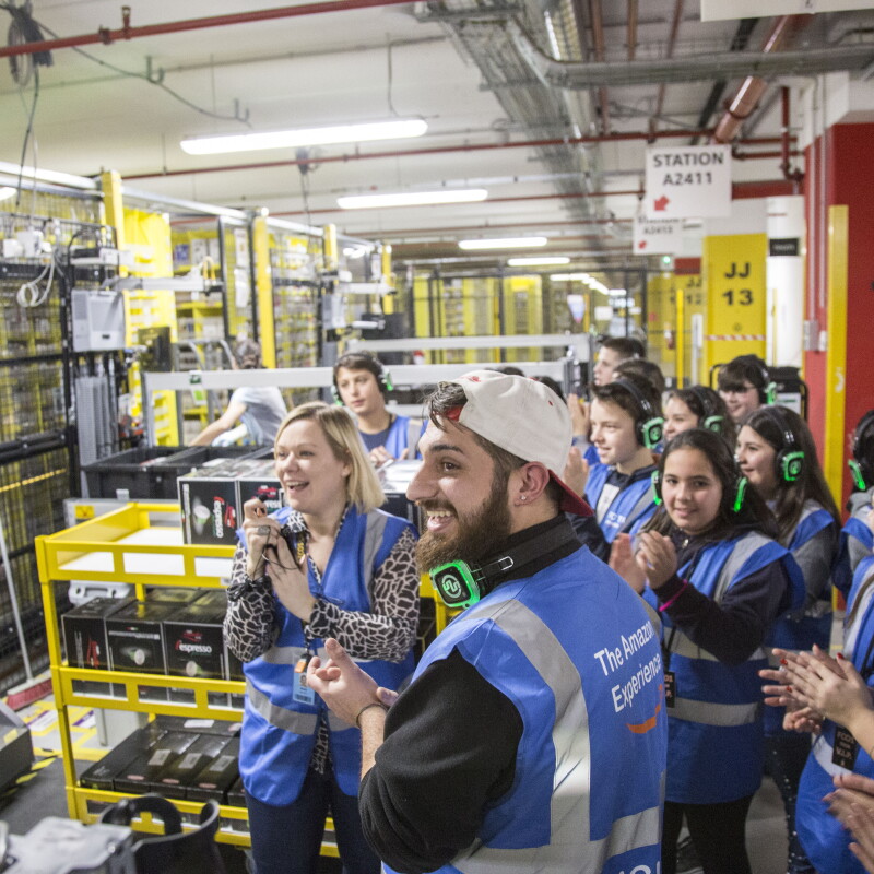 Foto di gruppo di visitatori di un magazzino Amazon durante un tour