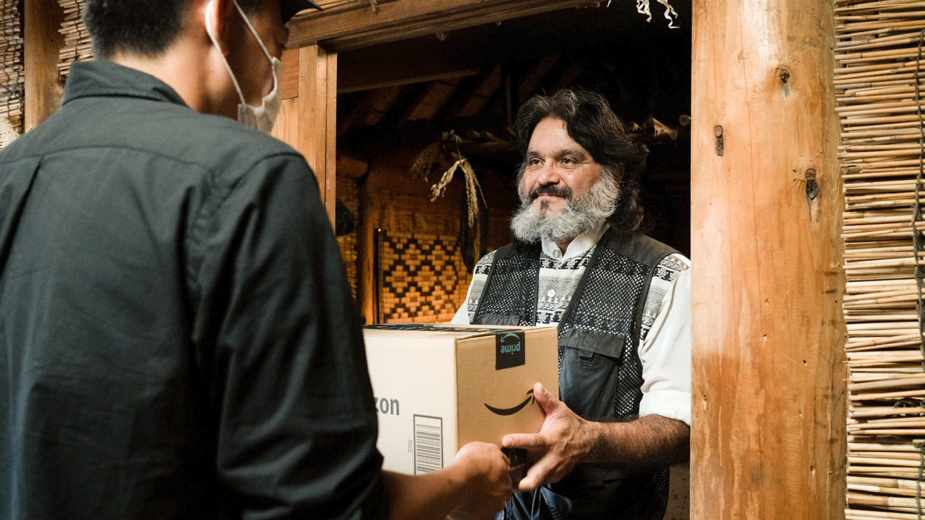 Debo is handed his Amazon package from an Amazon delivery driver.