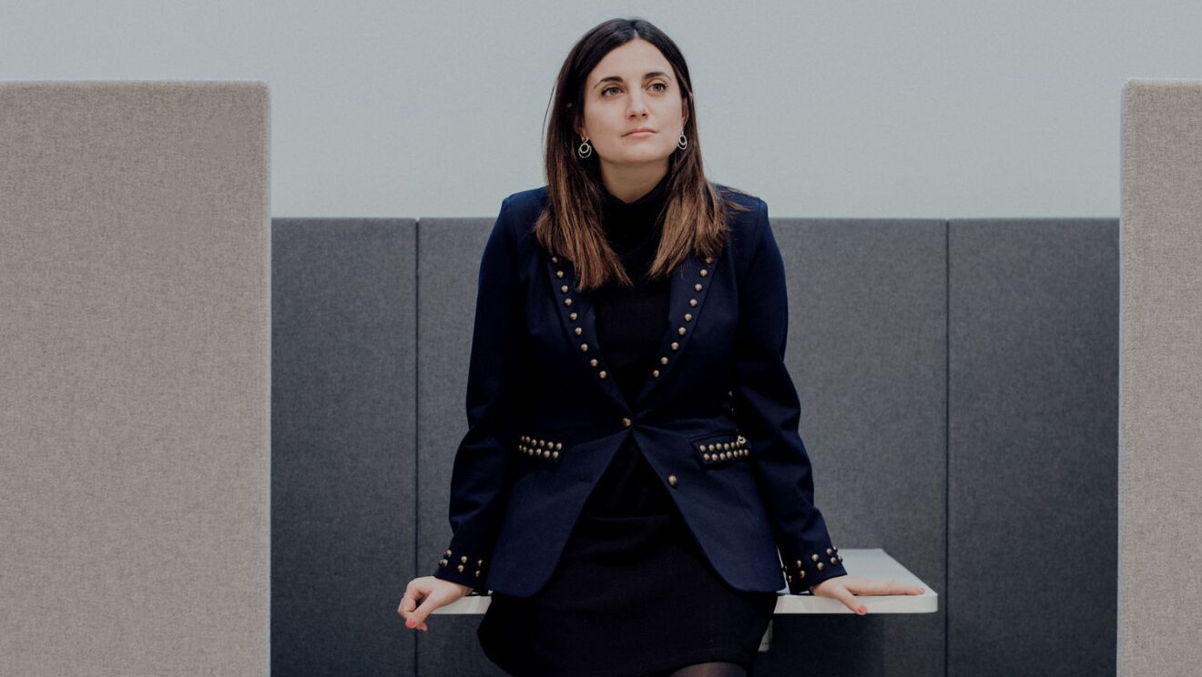 Nuria Pastor es licenciada en Psicología y MSc en Neurociencias y CEO de Humanitcare. Con una americana con tachuelas doradas y un jersey de cuello alto debajo. Está mirando al horizonte y tiene el pelo castaño gris por el hombro. 