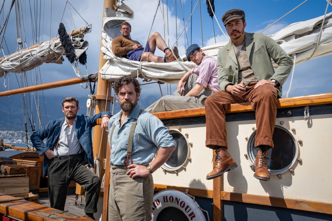 The cast of The Ministry of Ungentlemanly Warfare standing on a boat with blue skies in the background