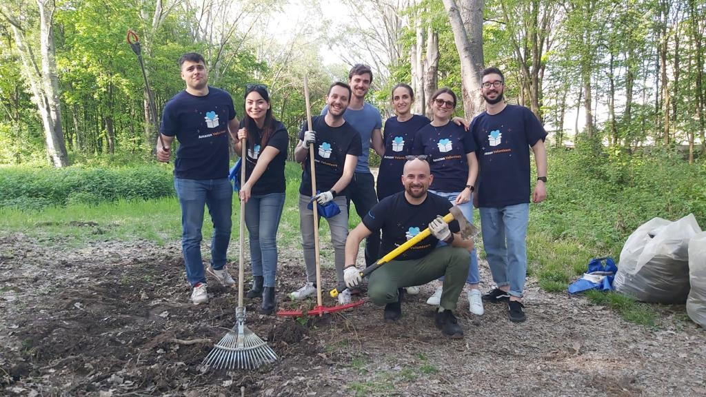 A group of Amazon employees is wearing blue vests and carrying tools to pick up garbage 