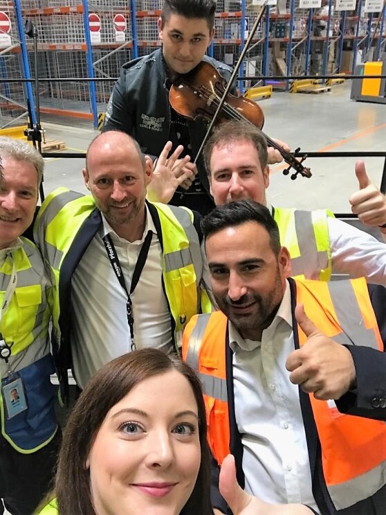 Selfie mit fünf Amazon Mitarbeitern, davon eine junge Frau, und dem jungen Geiger