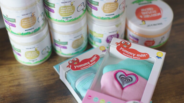 A photo of Yummy Mitt products such as a teething mitten and shea butter.