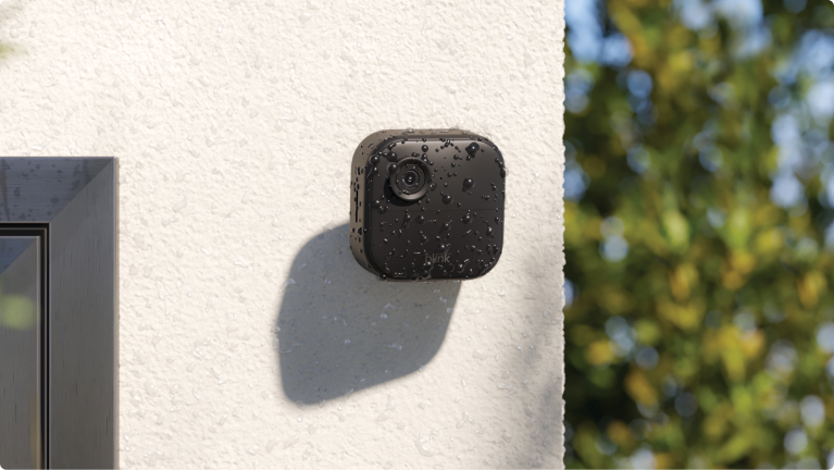 A waterproof Blink security camera covered in rain, mounted to the outside of a house