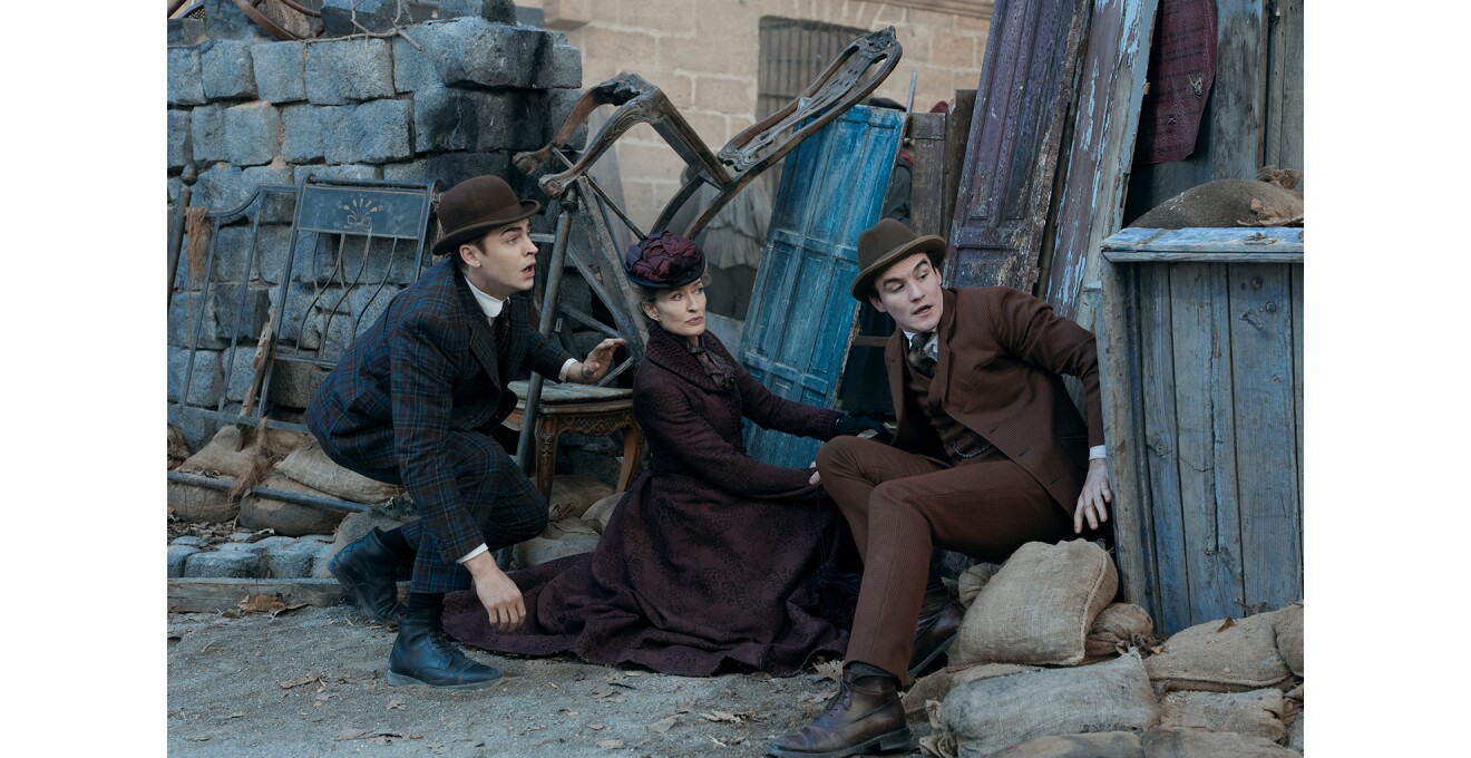 粗大ごみ置き場のような屋外で物陰から右方向の様子をうかがう3人の人物。