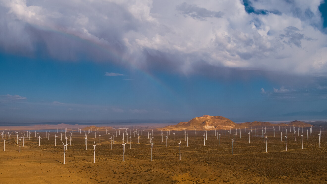 An aerial view of a wind farm in a mountainous desert landscape.