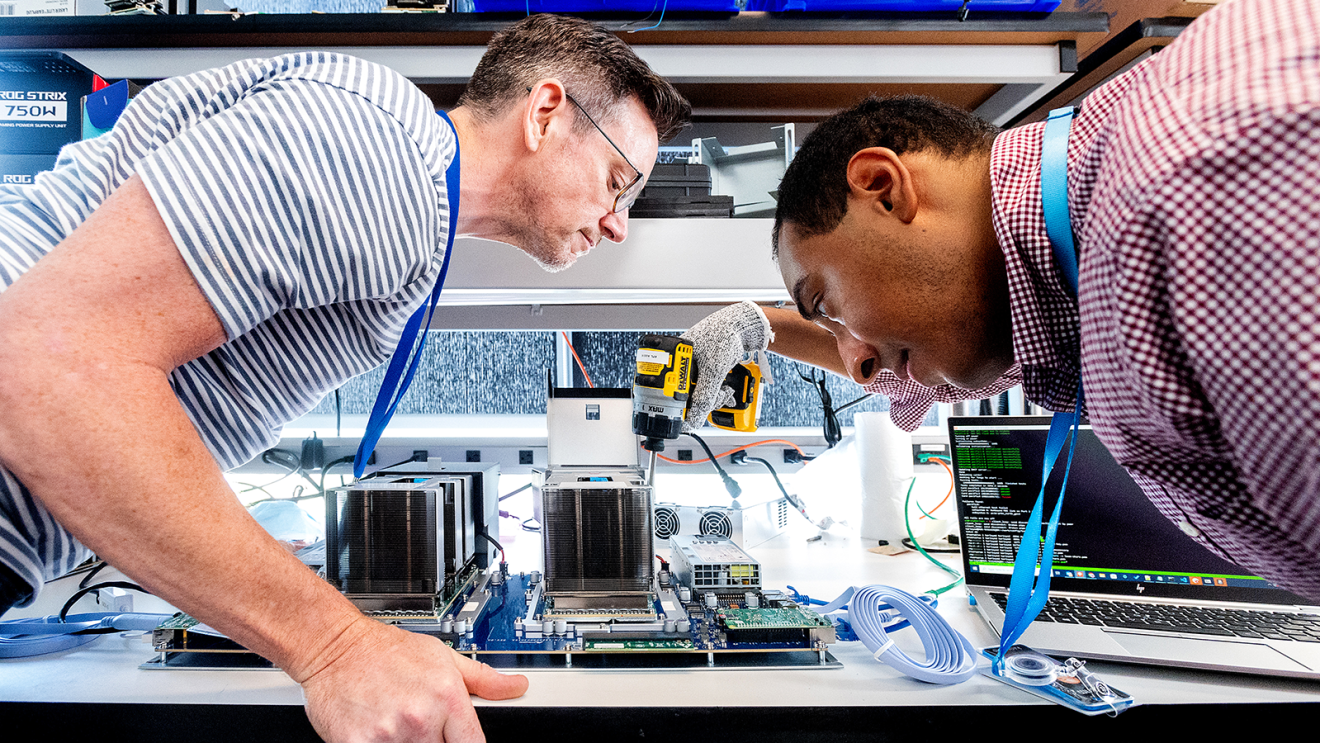 Two engineers examining computer components on workbench
