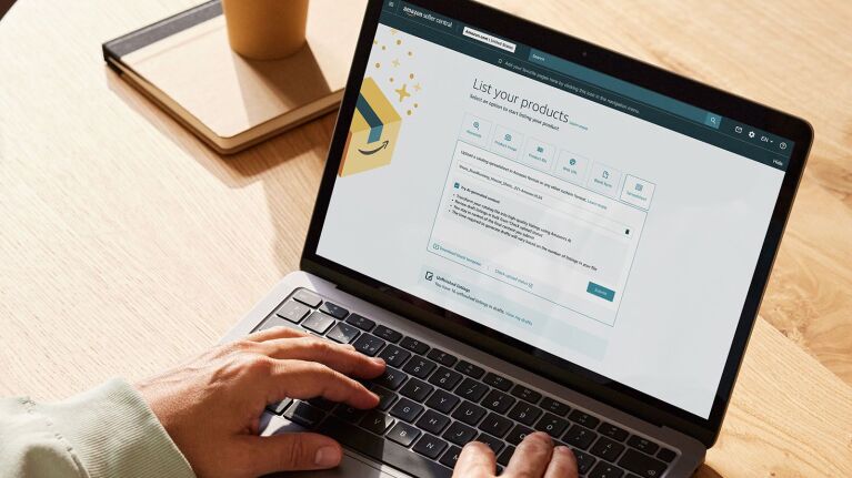 Ahşap masanın üzerinde Amazon satıcı ürün listeleme sayfasını gösteren dizüstü bilgisayar