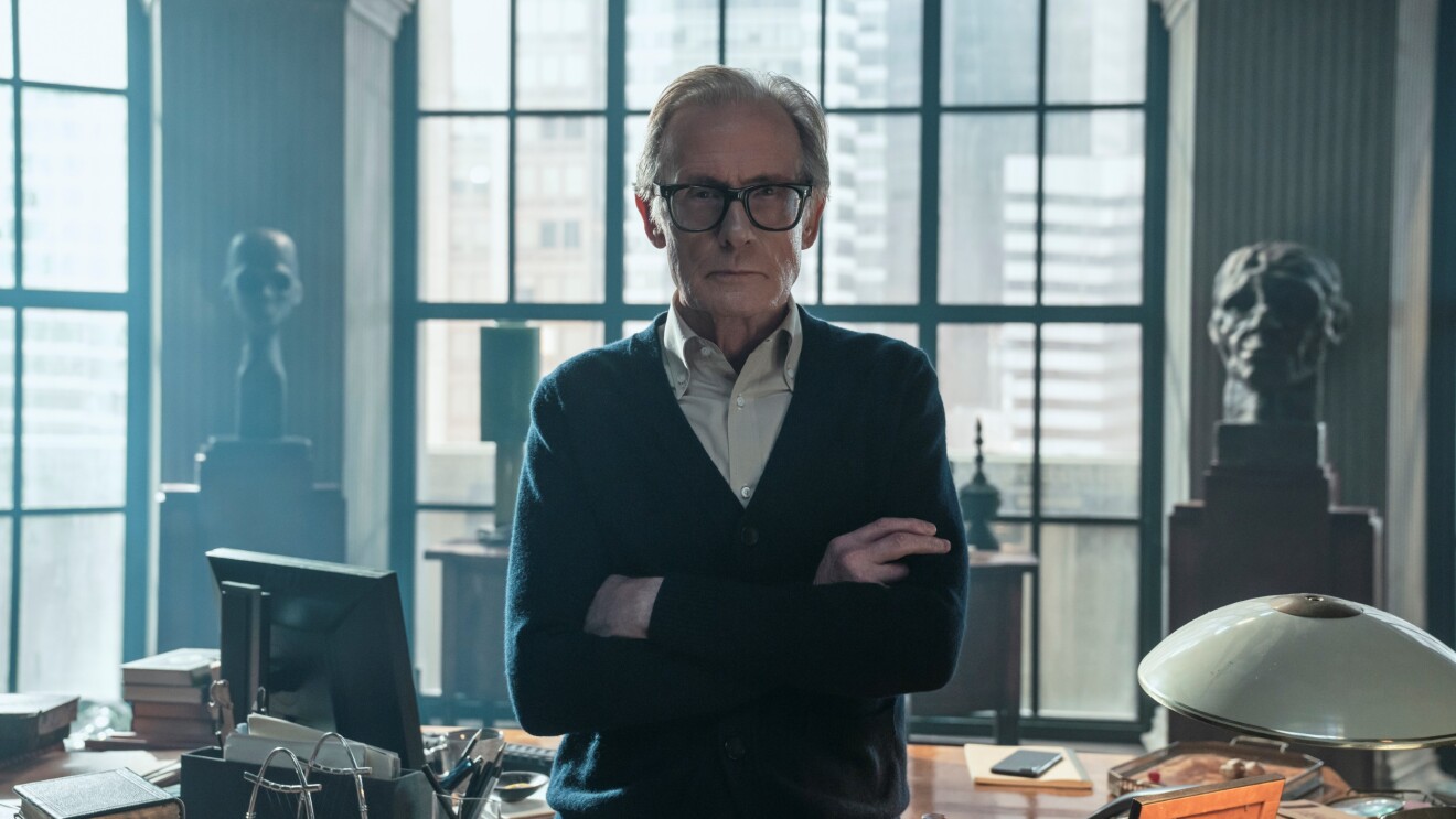 Distinguished gentleman with arms crossed before large windows in study