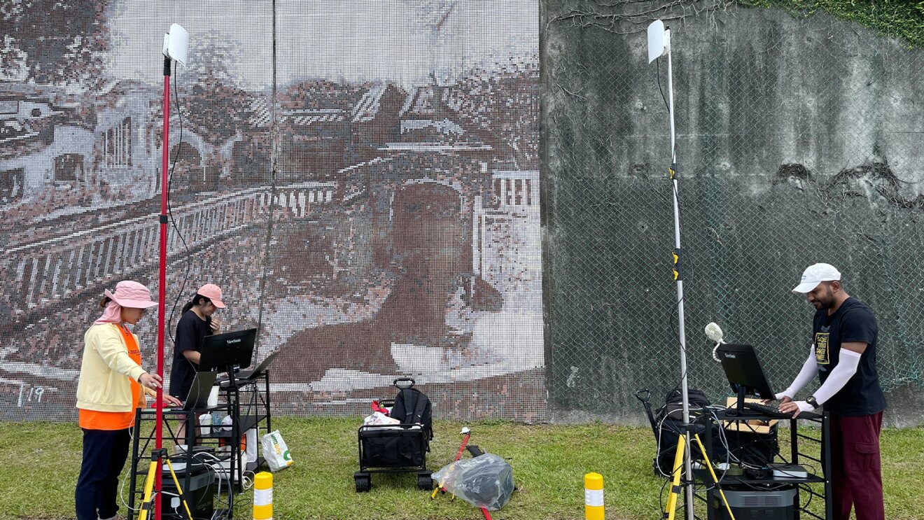 Field technicians operating gear near wall with city scene
