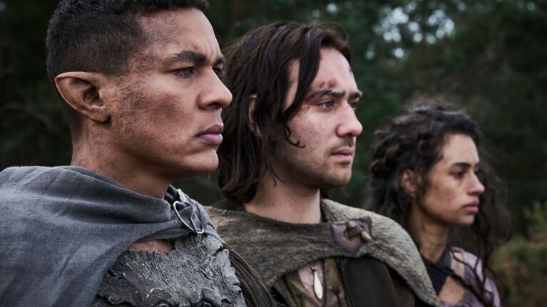 Three rugged characters in medieval-style attire looking intently ahead.