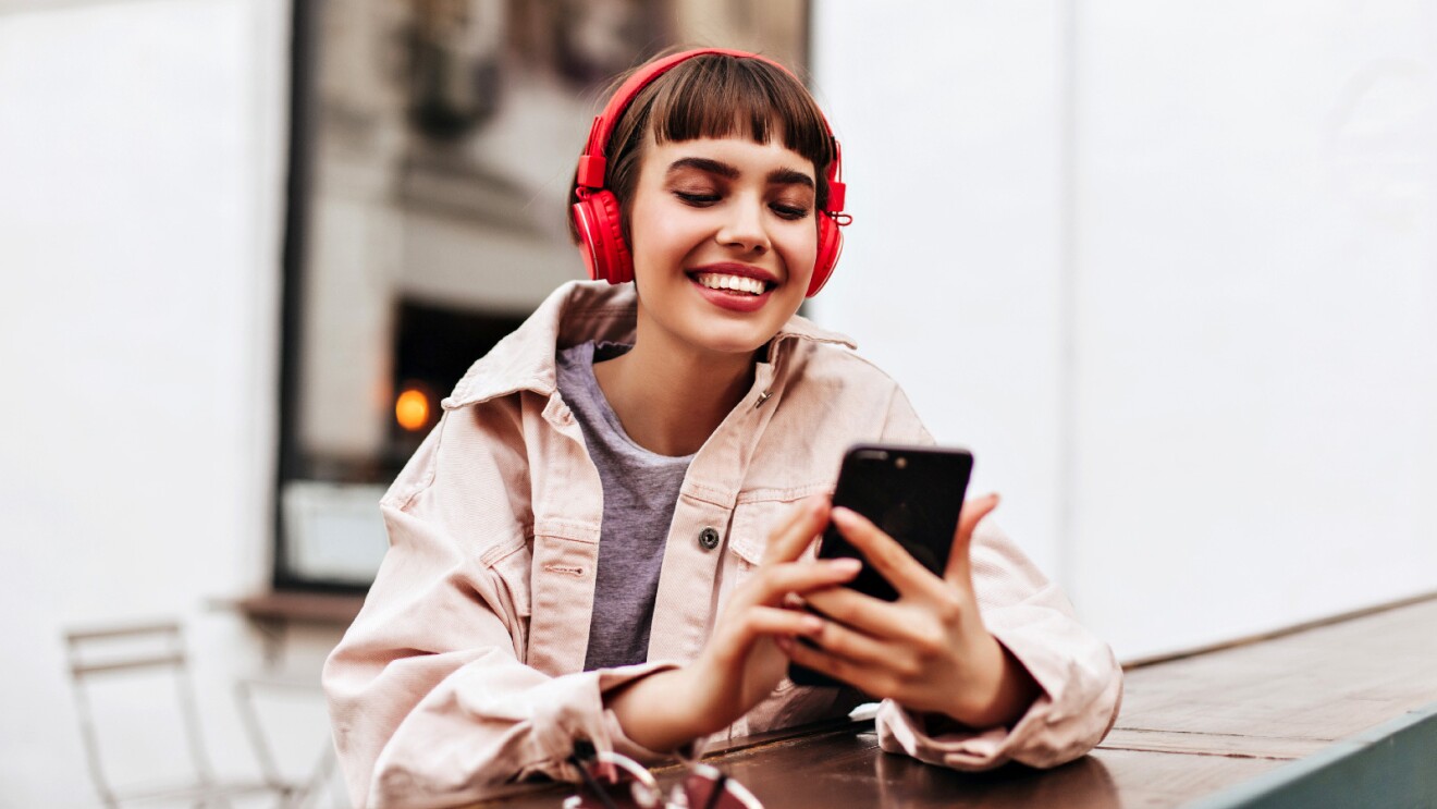 Prime Day 2023 live blog best deals: woman wearing red headphones while looking at her phone.