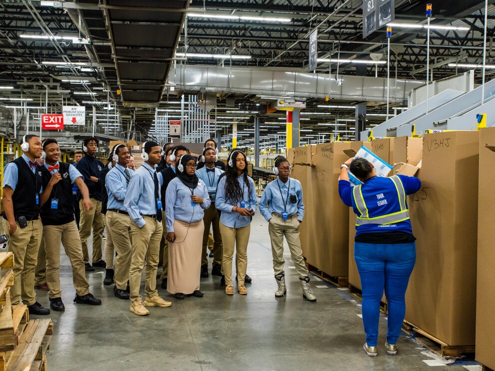 Students attend a tour of an Amazon robotics fulfillment center