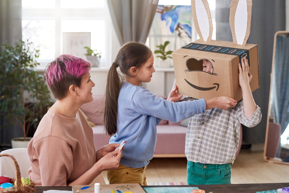 Ein kleiner Junge mit einer Amazon-Karton-Maske: Der Augenbereich wurde herausgeschnitten, so dass man seine Augen sieht. Der Smile Pfeil verkörpert einen lachenden Mund.