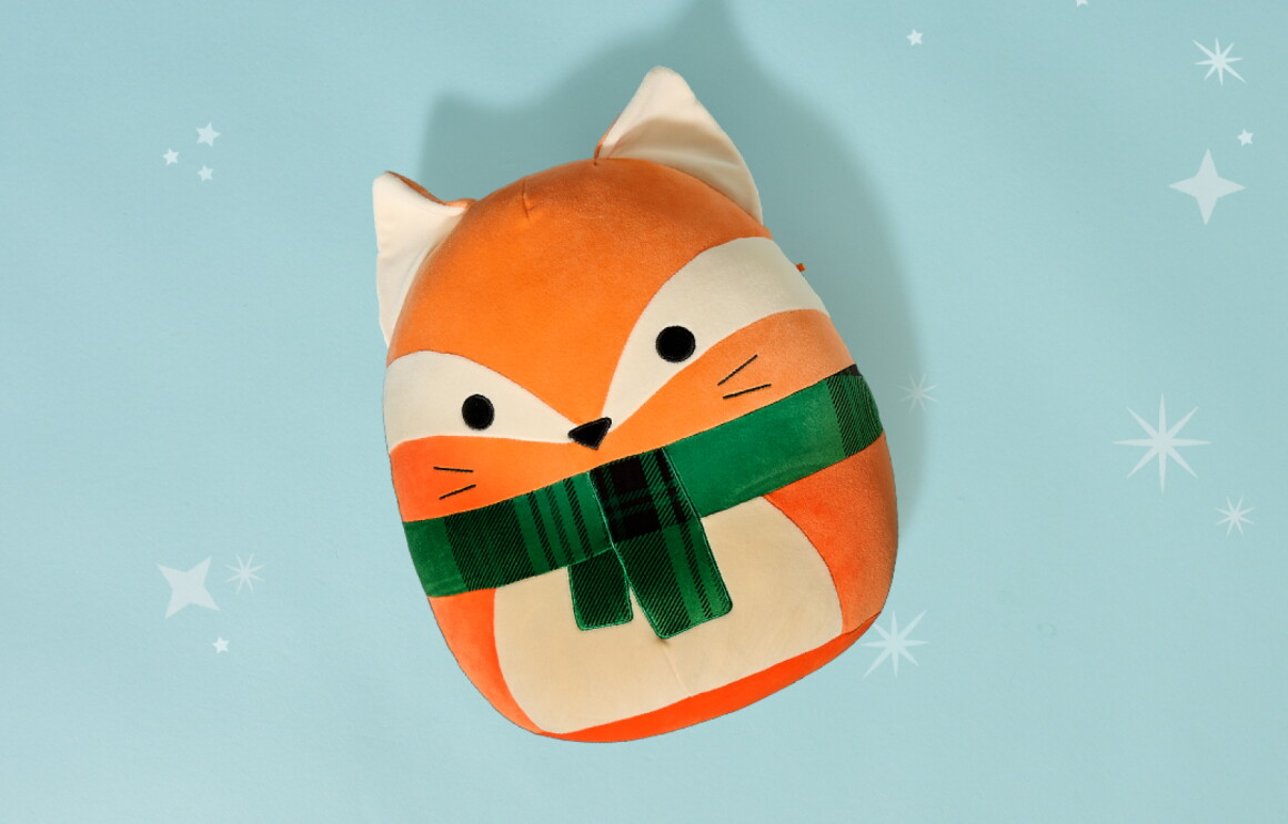 Cute fox plush toy with green scarf on light blue background