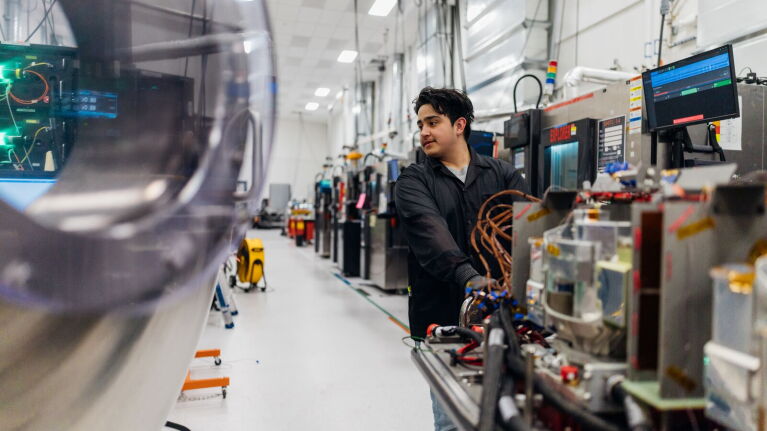 Technician assembling components at a manufacturing station with digital displays