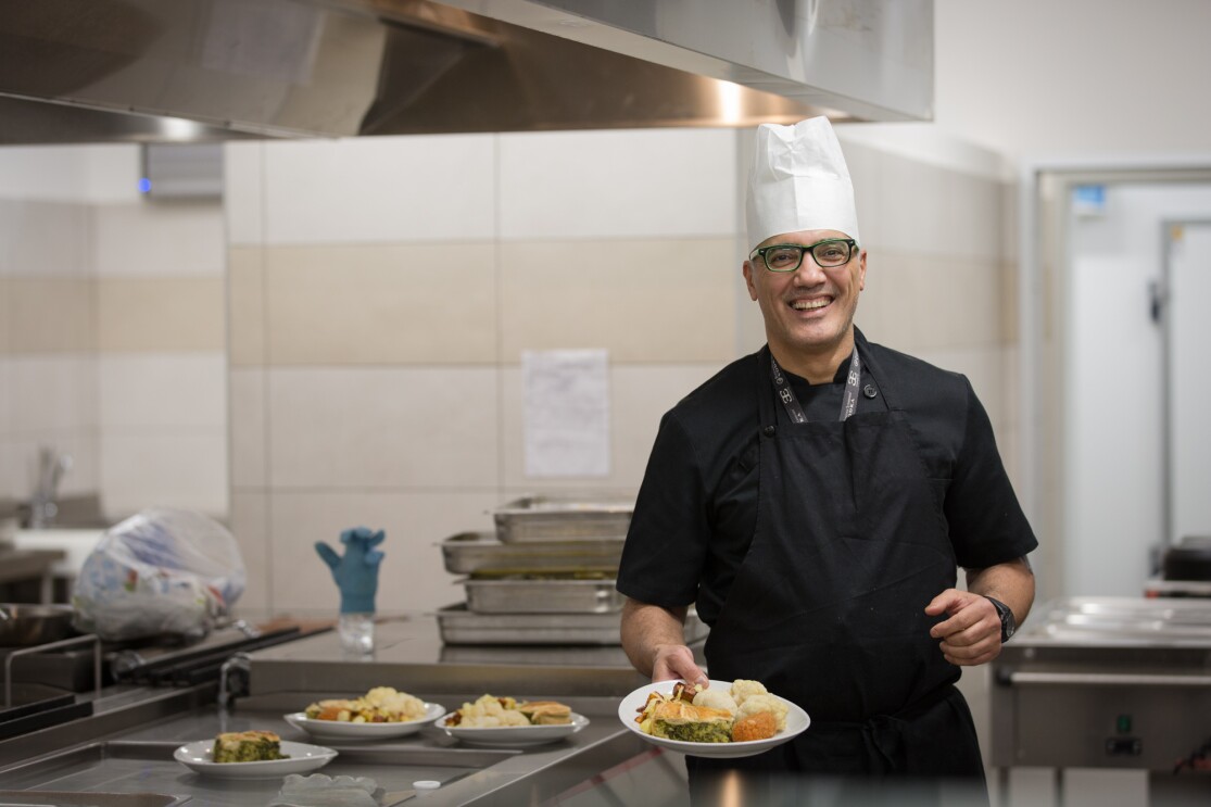 A chef holding a plate of food inside an Amazon fulfillment center in Italy.