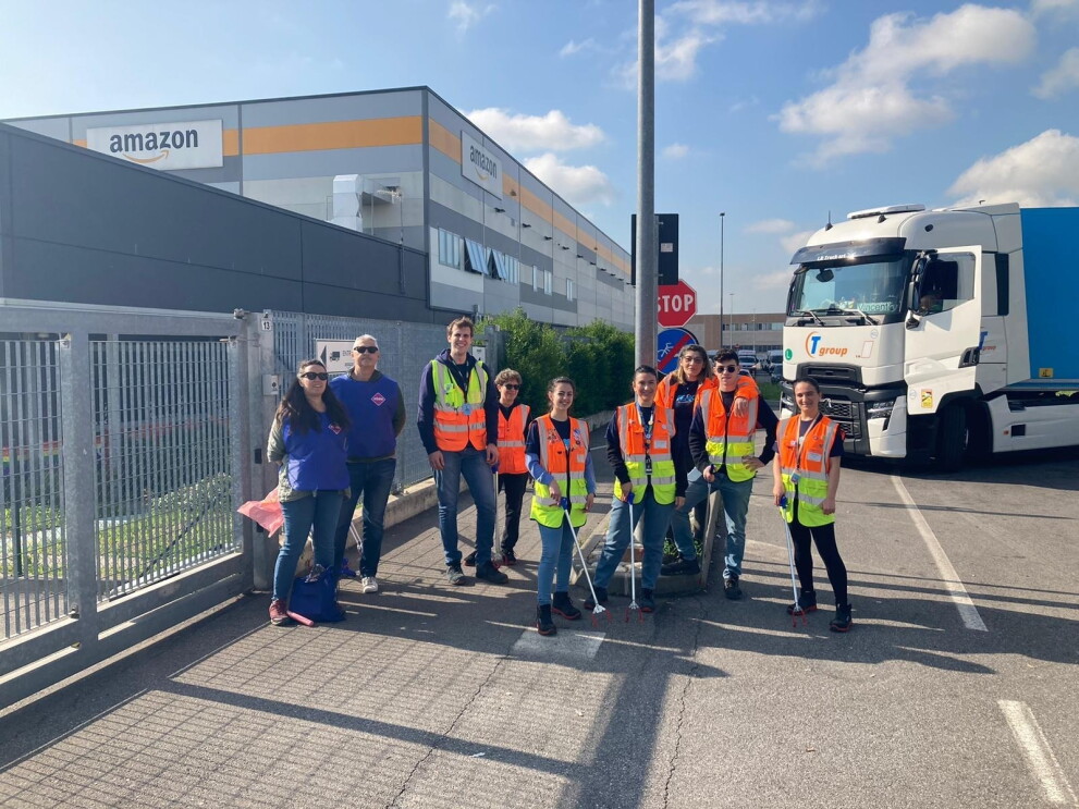 A group of Amazon employees is wearing blue vests and carrying tools to pick up garbage 
