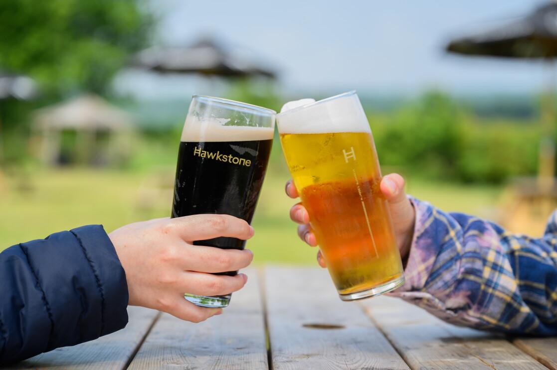 Two pint glasses in cheers at The Farmer's Dog in Burford, Jeremy Clarkson's proper British pub from Clarkson's Farm season 4