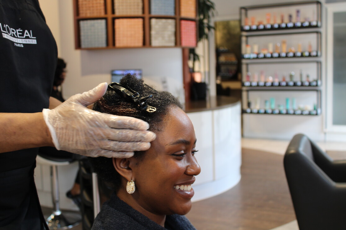 Hair stylist Korell in the middle of hair styling the client, Melissa 