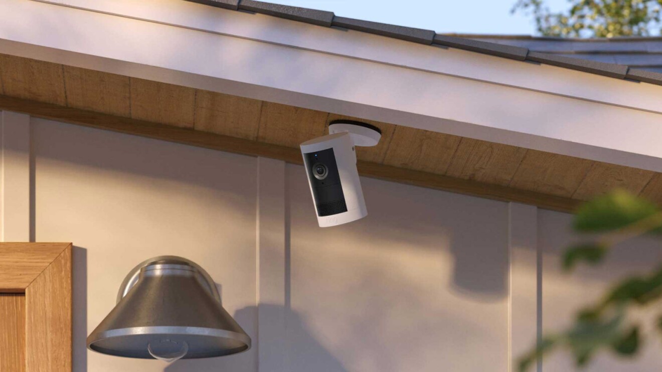 Security camera mounted under eave near outdoor light fixture