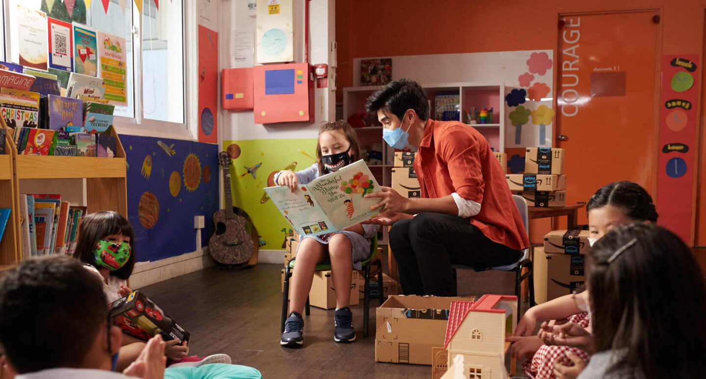 Nathan Hartono sits and reads a book with one of the beneficiaries 