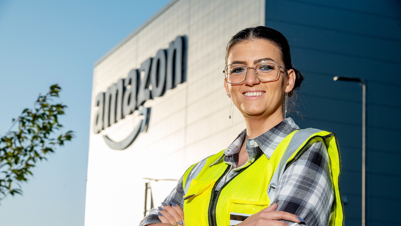 Amazon employee Diana Frunza in a safety vest while smiling outside a fulfilment centre
