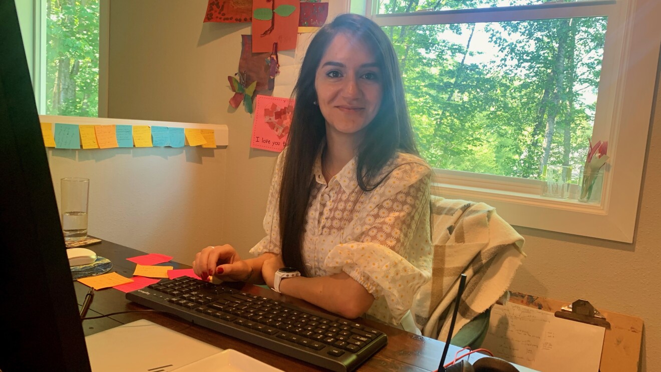 A woman smiles for a photo while sitting at her desk at home working.