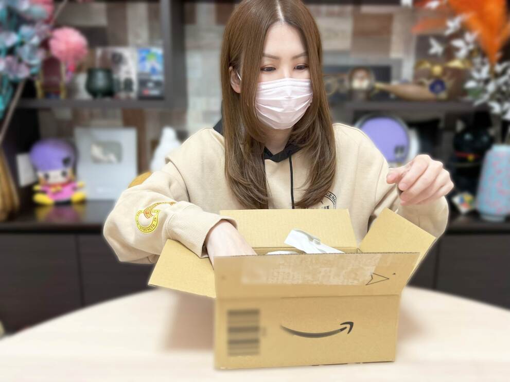 マスクをした女性がAmazonの箱を開けている。アジーンTV