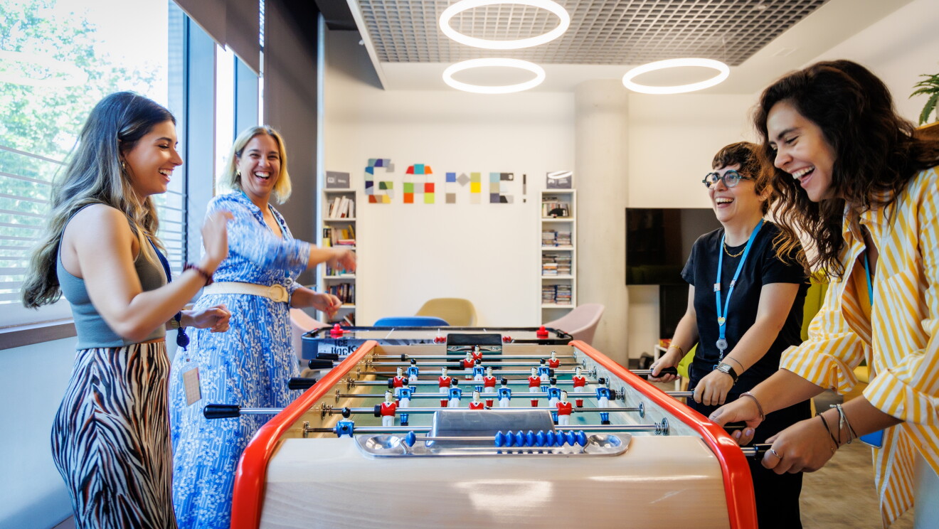 Cuatro mujeres jugando al futbolín en una oficina logística de Amazon.