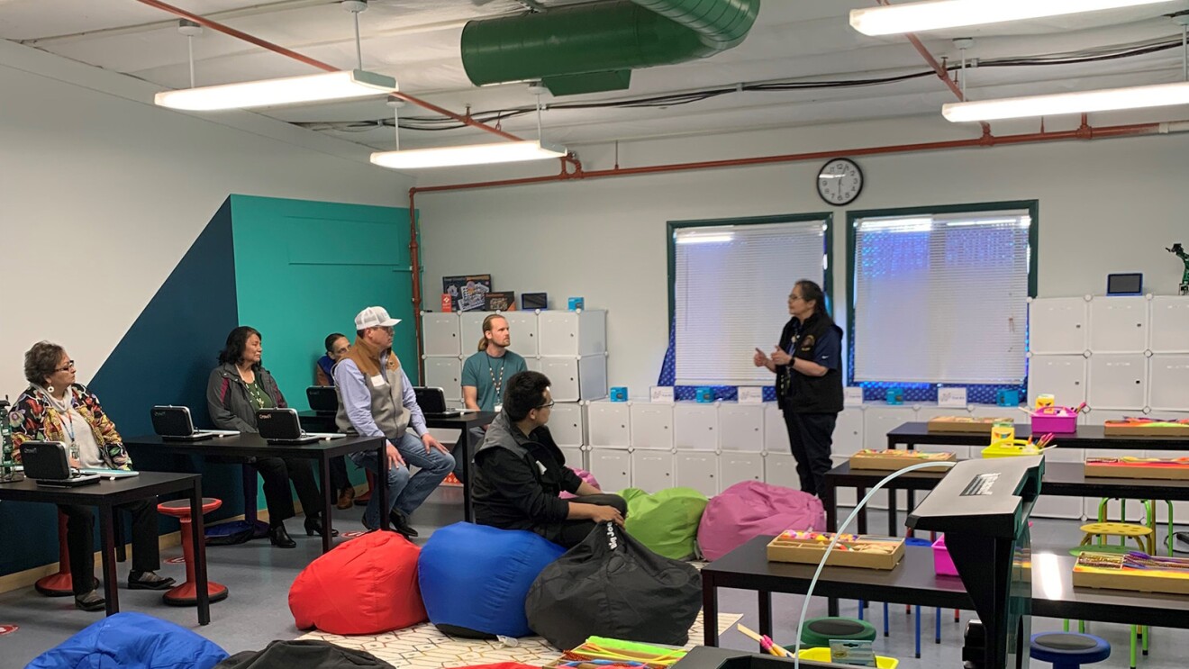 An image of adults sitting in a classroom listening to one person speaking at the front of the room.
