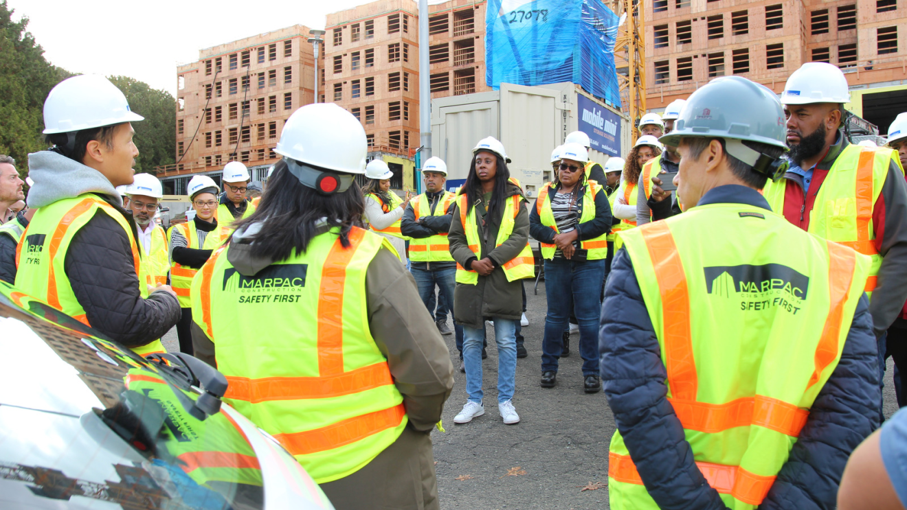 A photo of fellows from the Amazon Housing Equity Fund’s Housing Equity Accelerator Fellowship (HEAF) program, in front of affordable housing properties under construction in Seattle, Washington.
