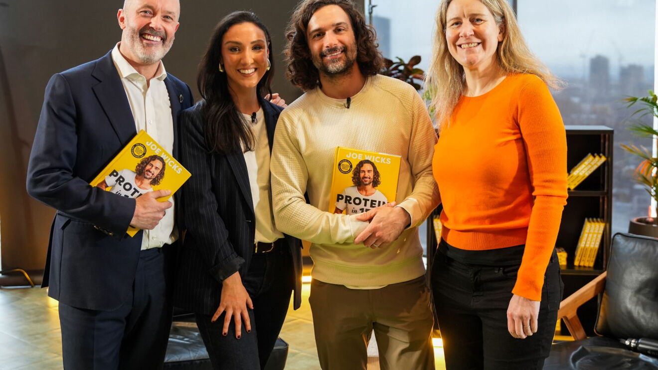 Four people smiling whilst holding Joe Wicks' new cookbook