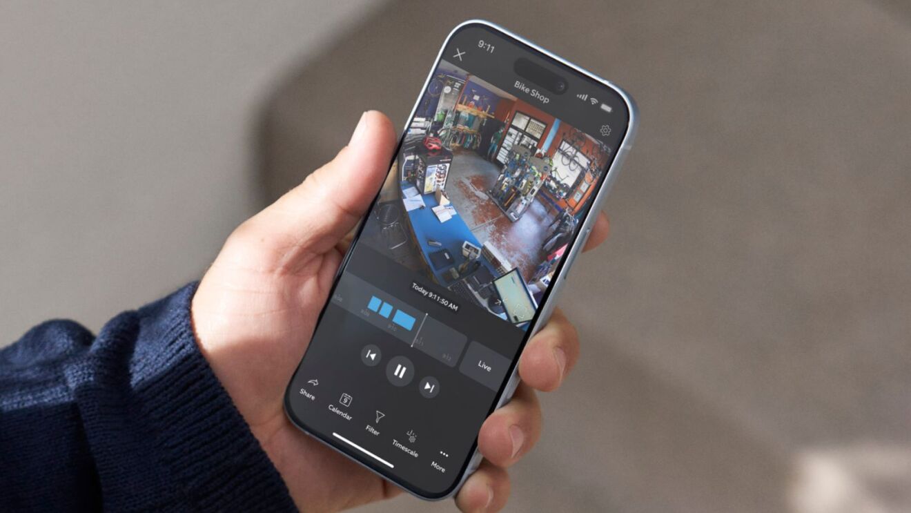 Hand holding iPhone displaying bike shop security camera feed from Ring