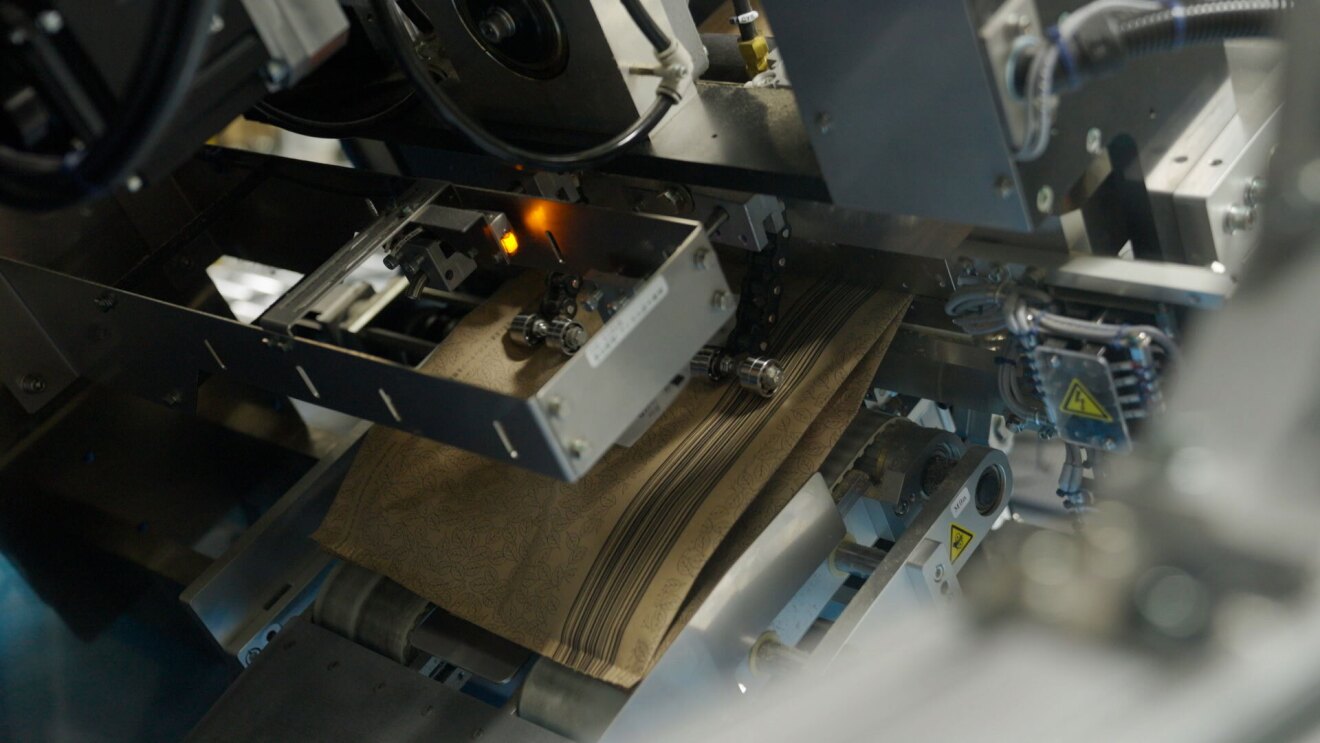 機械の間に紙袋が挟まれ、カットされている