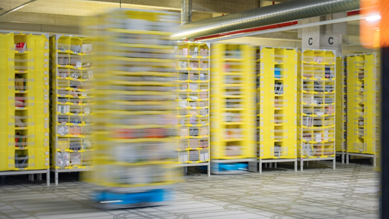 Fast-moving robotic system amid yellow storage racks
