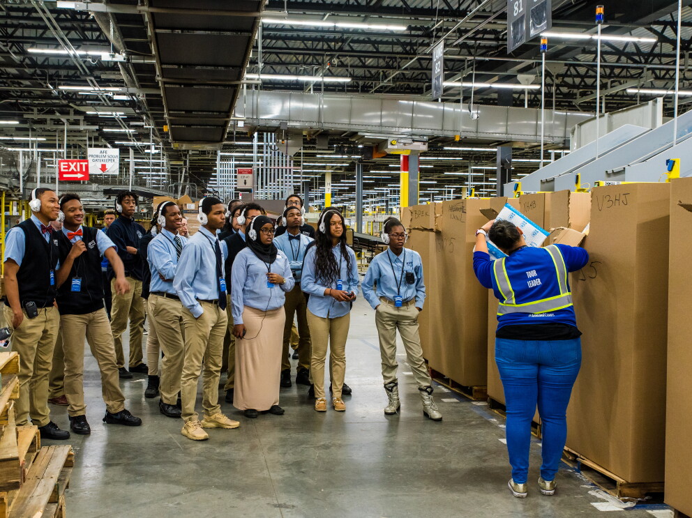 Students attend a tour of an Amazon robotics fulfillment center