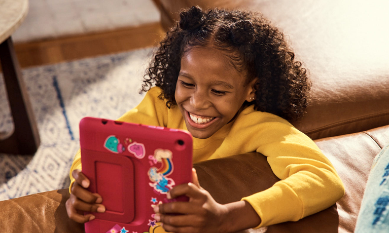 Young girl smiling while playing with her kindle