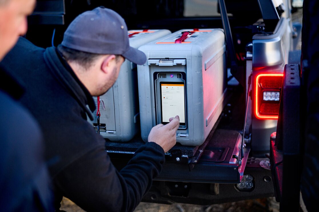 An image of a man using a touch screen on a large metal suitcase.