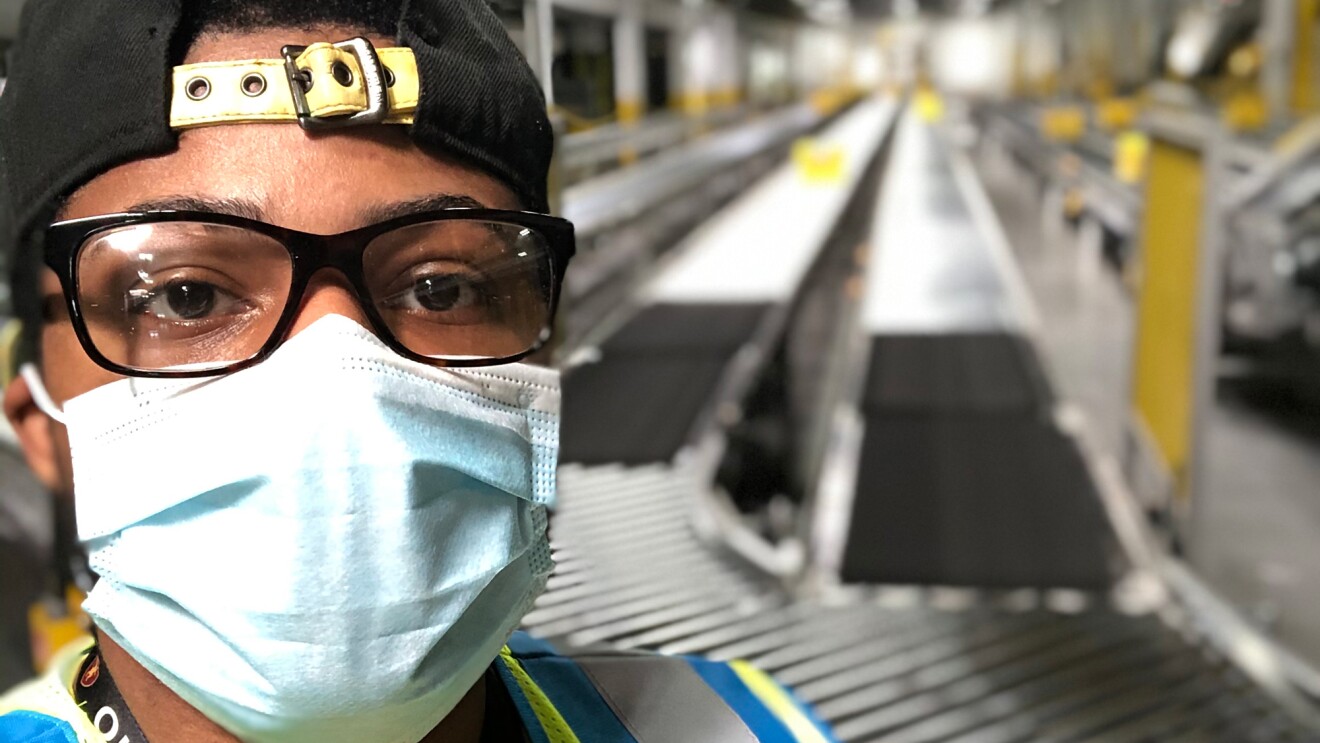 Close-up of a man wearing a protective mask in a large workspace.