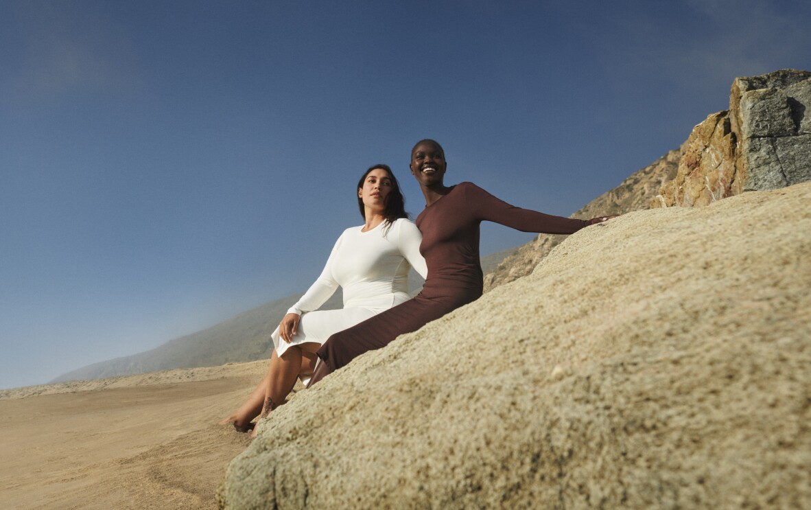 Amazon Aware clothing models lounging on a sand-coloured rock