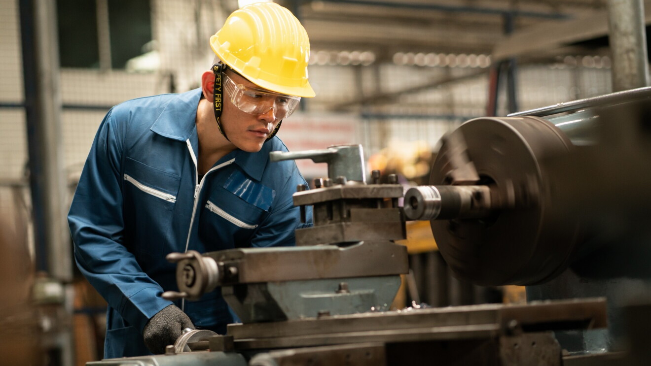 A man wears safety gear has he works with machinery.