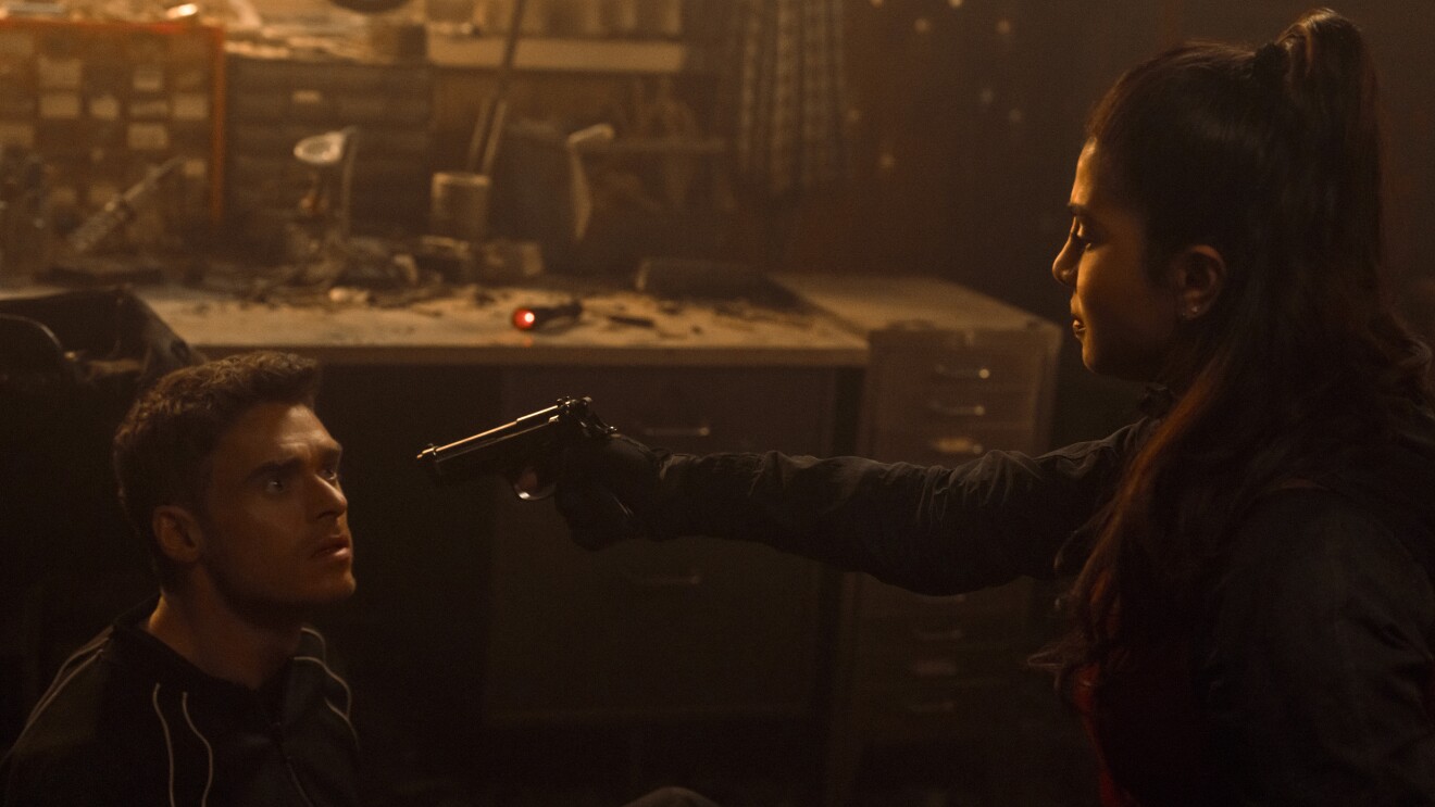 Citadel S2: Woman pointing a weapon at a man in a dimly lit workshop