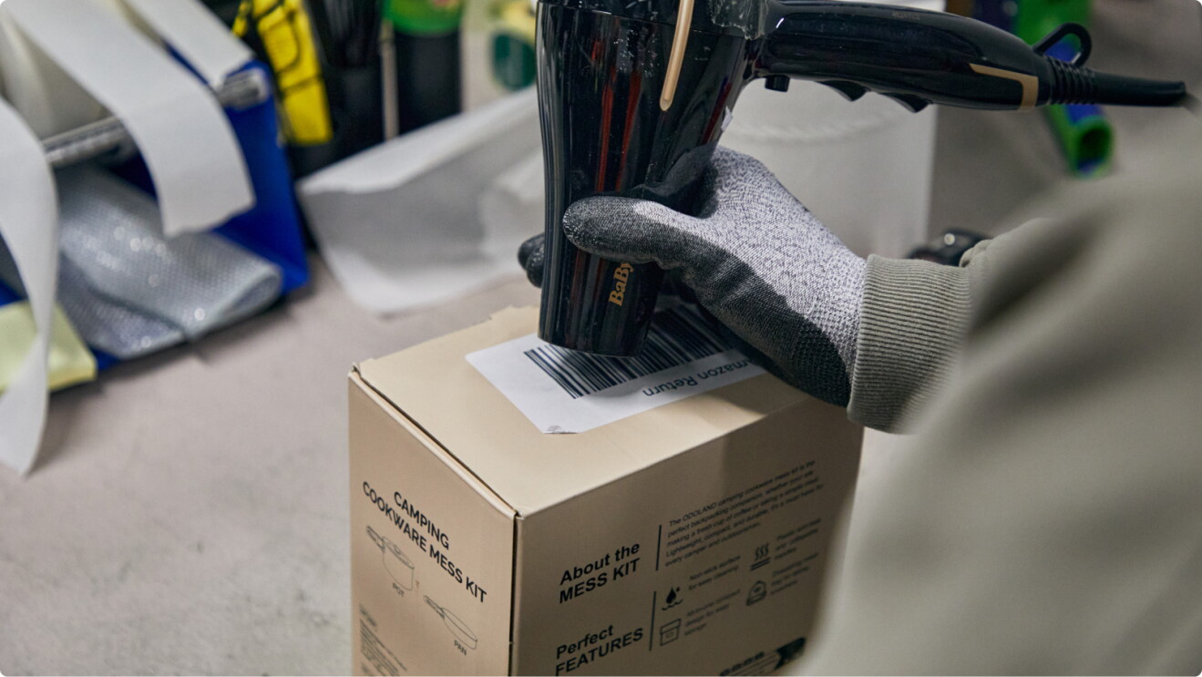 Gloved hand removing barcode label sticker using hairdryer heat