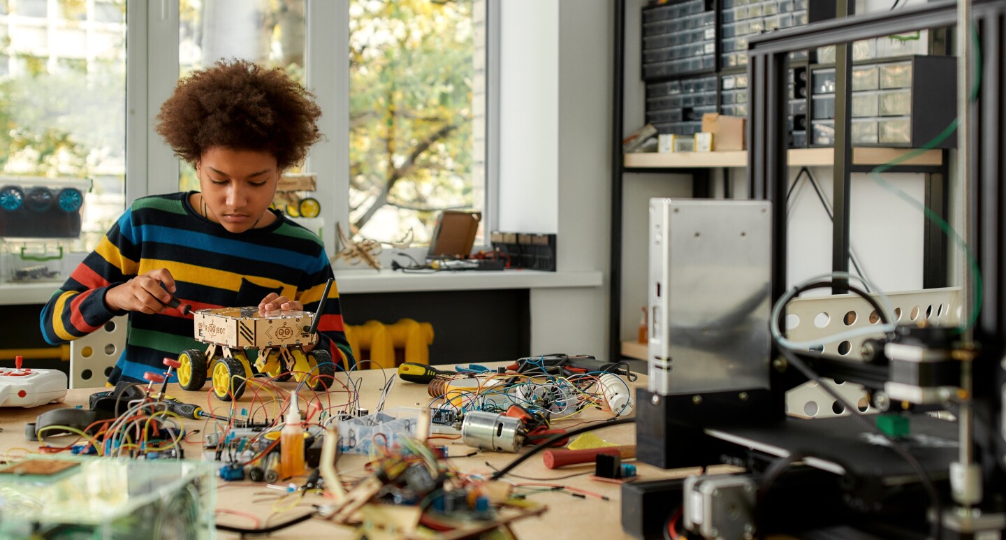 A photo of a student working on a robot within an engineering classroom.